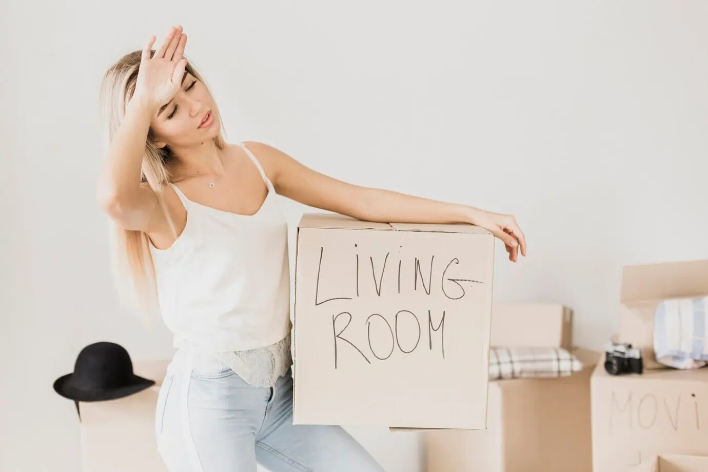 Уставший молодой мужчина держит картонную коробку.